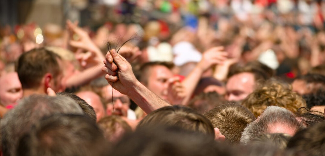 Crowd at a concert seen from behind with raised hands