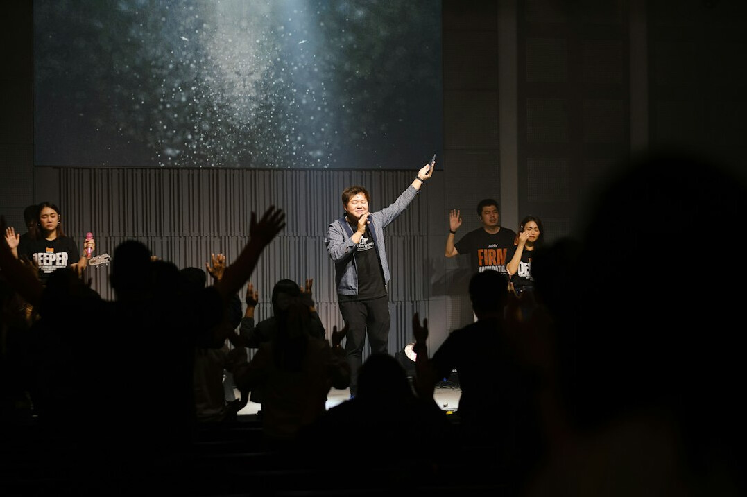 Speaker on a stage with a spotlight in front of a seated audience