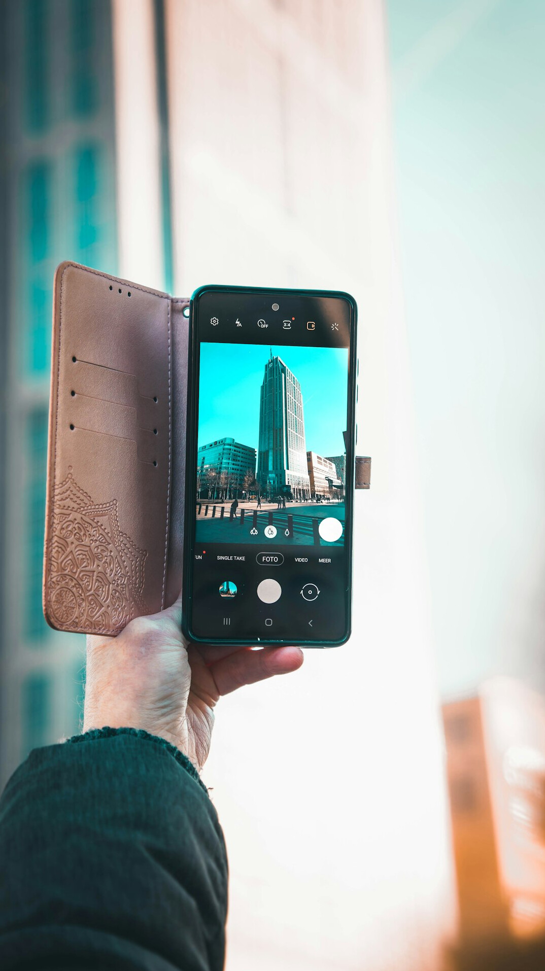 Hand holding a smartphone with a blurred city in the background